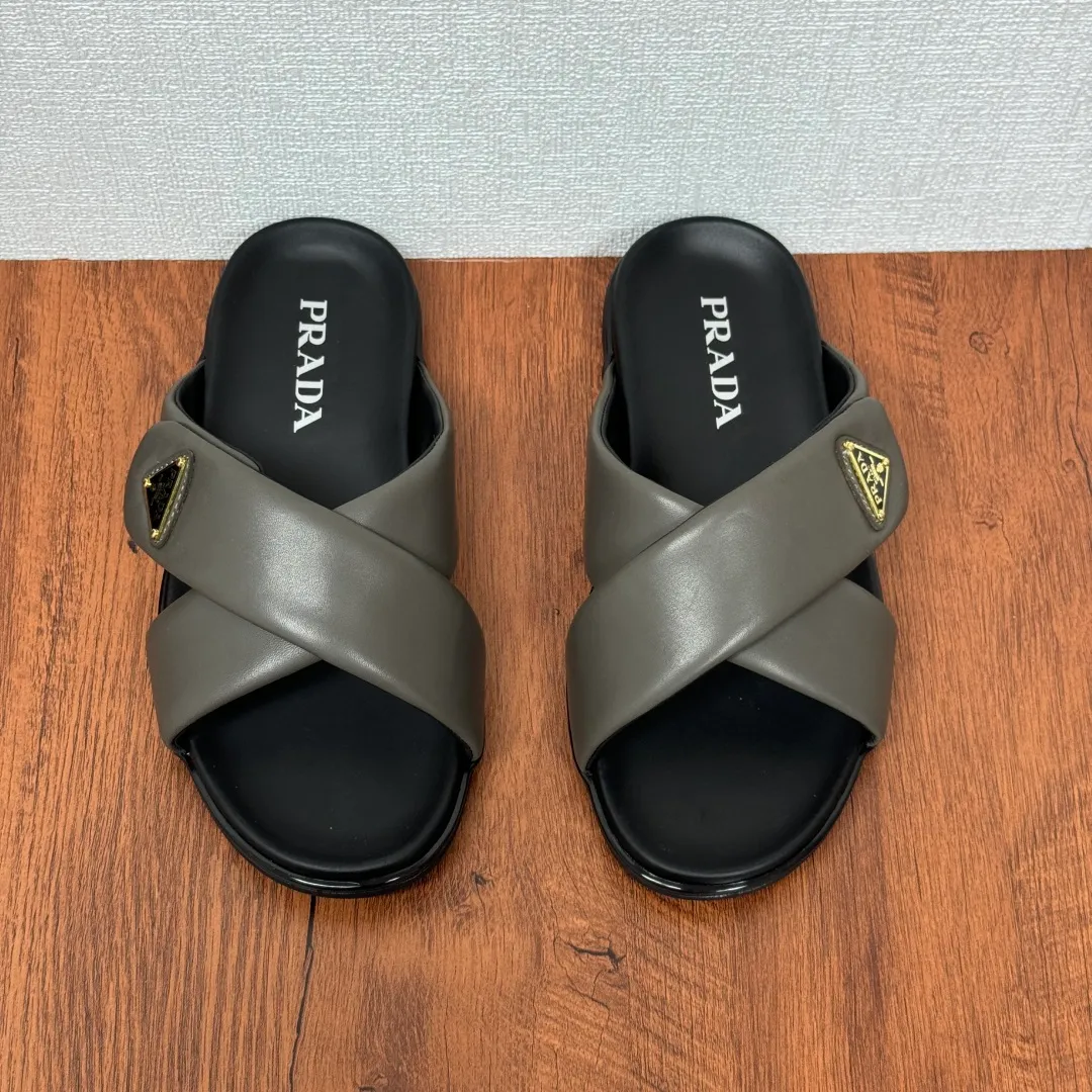 Batch 580 Prada/Prada's new men's leather cross slippers. Velcro closure can finely adjust the size. Calf leather light luxury slippers. Thick soft calf leather wraps the upper. Fat but soft rubber lazy style, soft and comfortable, excellent foot feel. Genuine leather bottom layer, cross style, with a Velcro closure buckle, easy to adjust the appropriate size, and a perfect fit for the wearing experience. The enamel gold triangle logo highlights the brand's classic features. Lightweight rubber thin sole, high foot comfort! Complete package! Size: 39-40-41-42-43-44-45 Leather shoe size Item number: 2X7132 Gray